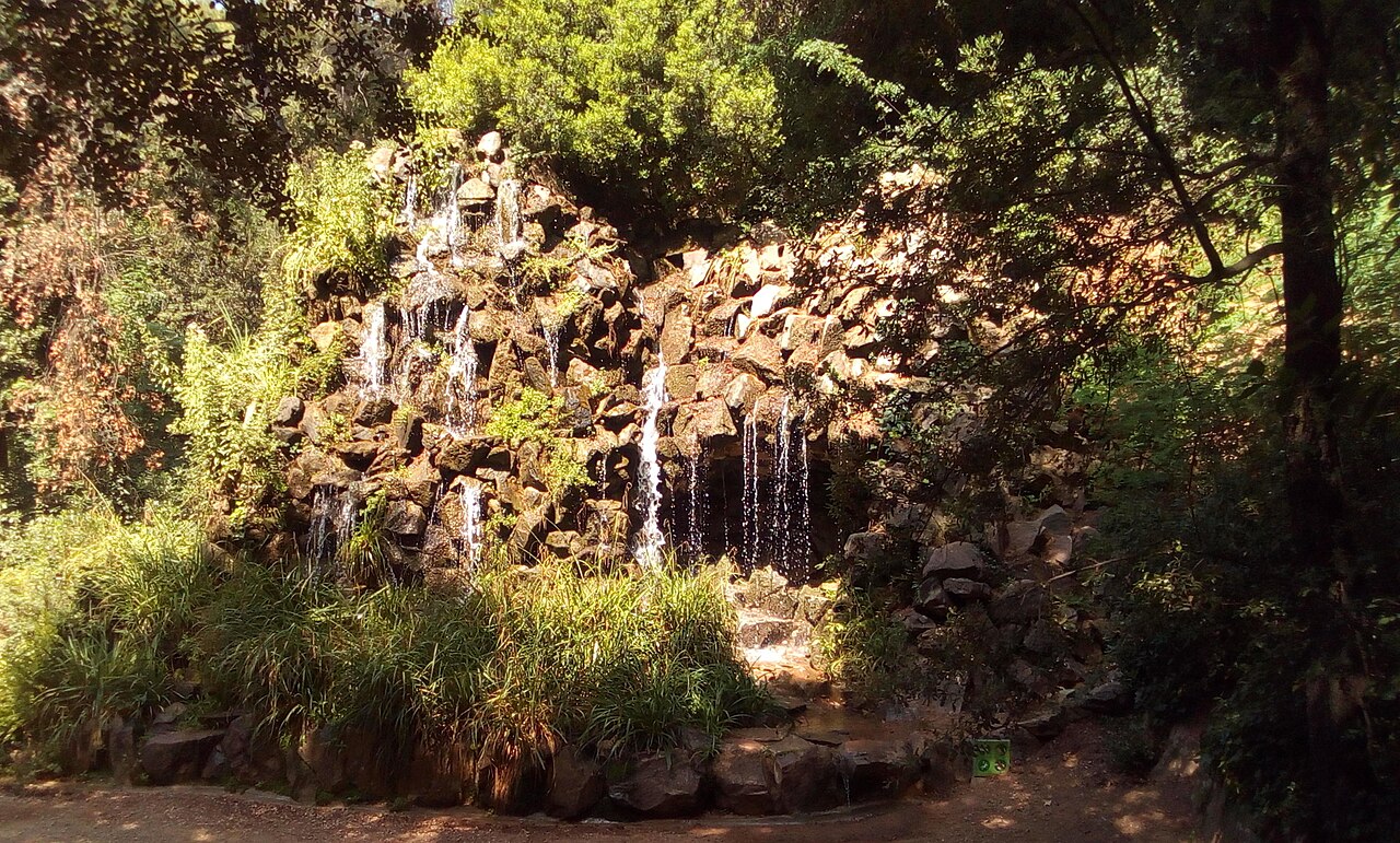 Salto de agua entre rocas y vegetación frondosa en la Cascada del Jardín Romántico de Horta