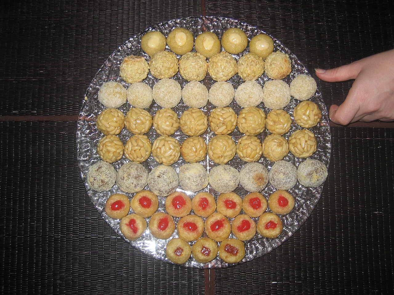 Bandeja de panellets tradicionales de piñones, almendra y membrillo recién horneados para La Castanyada en Barcelona
