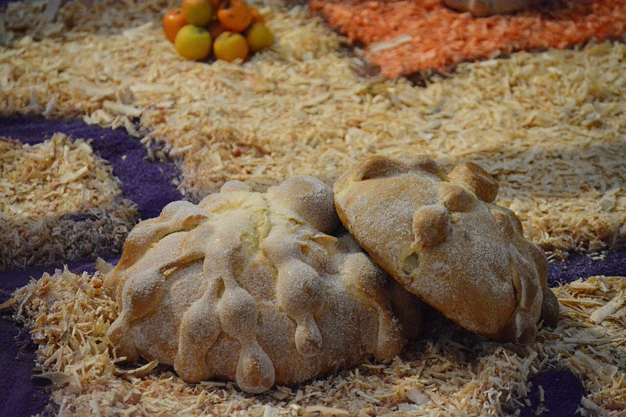 Pan de muerto tradicional mexicano espolvoreado con azúcar y decorado con huesitos de masa sobre la ofrenda