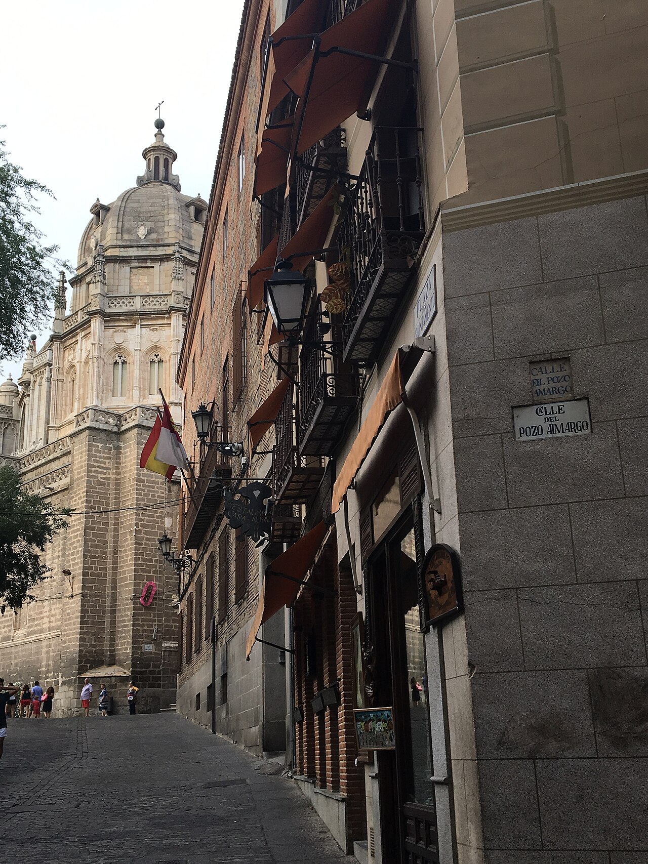 Placa histórica de piedra de la Calle del Pozo Amargo en Toledo con la cúpula de la Catedral al fondo