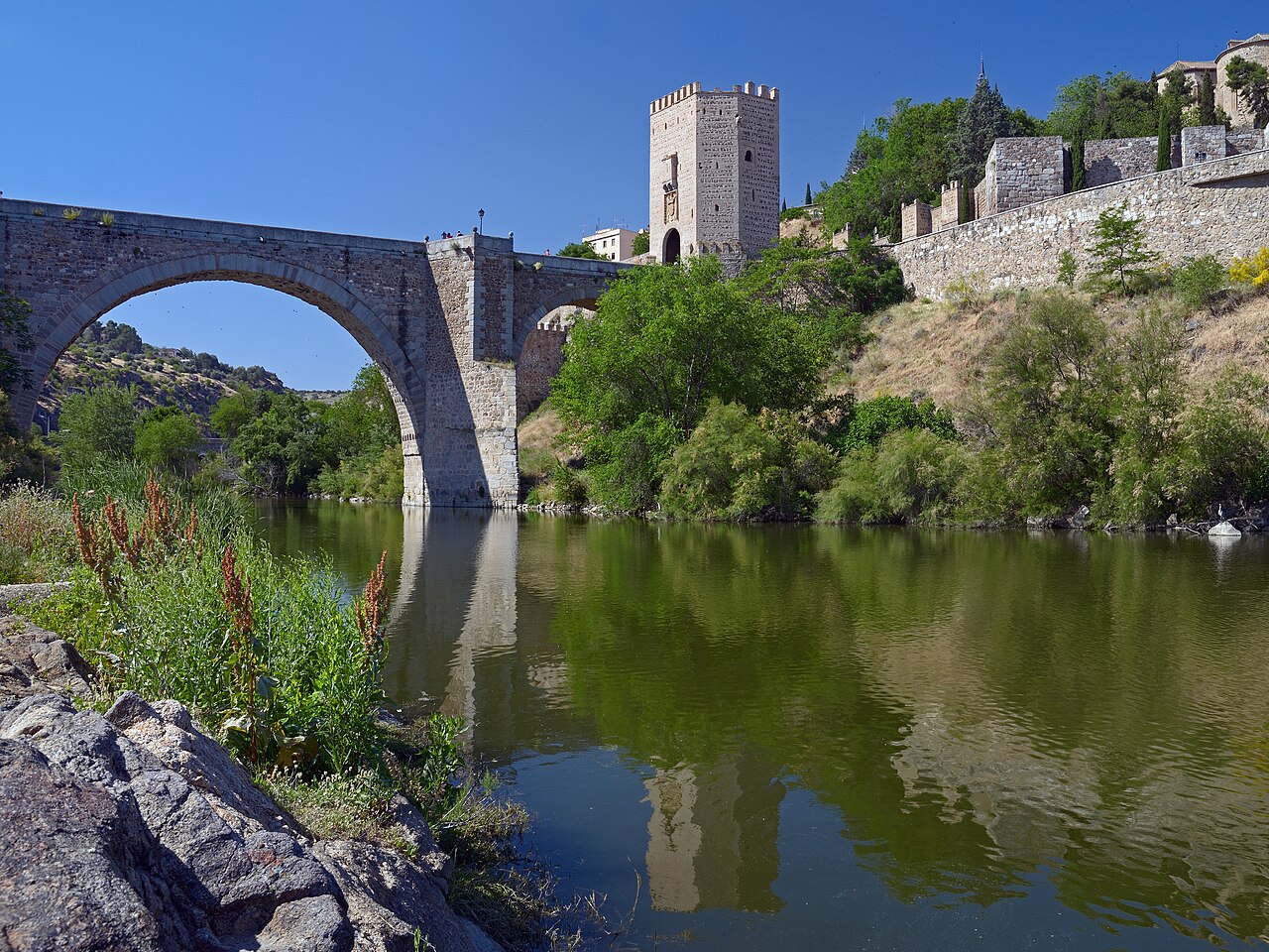 Puente medieval de Alcántara y murallas históricas de Toledo sobre el río Tajo