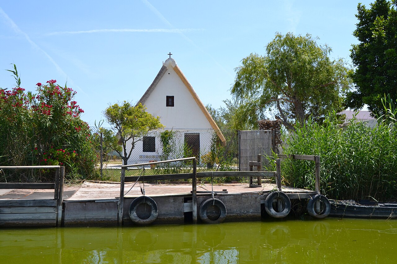 Barraca valenciana tradicional frente al canal y embarcadero de madera en El Palmar (L'Albufera)